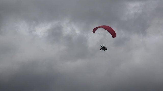 Parachute with motor flying on dark cloudy sky, dangerous flight