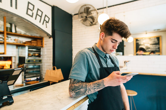 Young man using mobile phone in pastrami sandwich bar