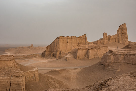 man standing on viewpoint overlooking rugged desert landscape, kalut, iran