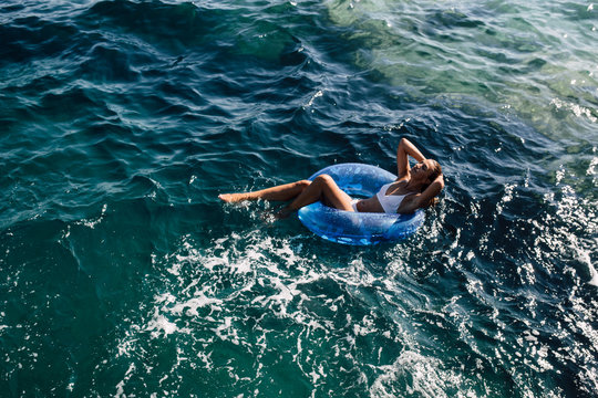 Above shot of a woman sunbathing on the water surface, laying in the rubber swim ring