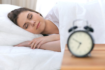 Beautiful young and happy woman sleeping while lying in bed comfortably and blissfully smiling