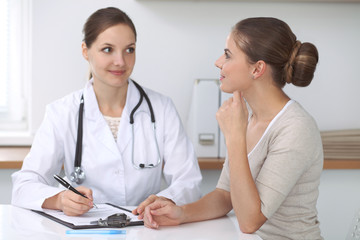 Doctor and  patient  sitting at the desk. The physician or therapist makes a diagnosis. Health care, medicine and patient service concept