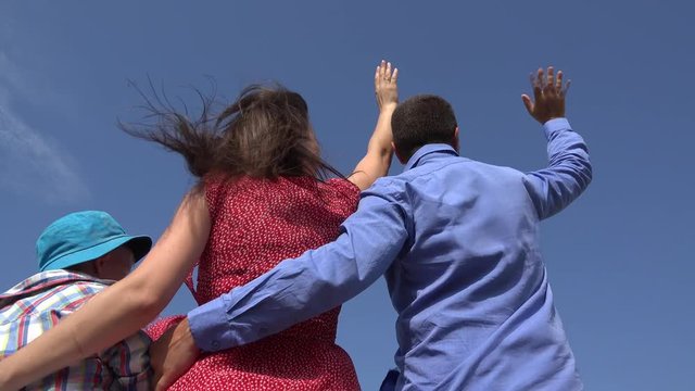Slow motion of big plane passing on blue sky over a family, parents waving hands