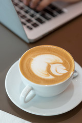 Hot art latte coffee cup on wooden table