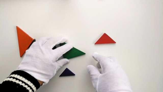 man playing wooden tangram and shaping it like a flying piegon on white