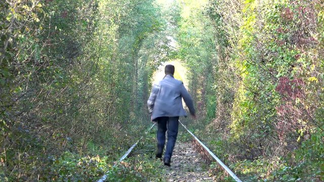 Man running on railway, waiving hands, lost train, autumn landscape