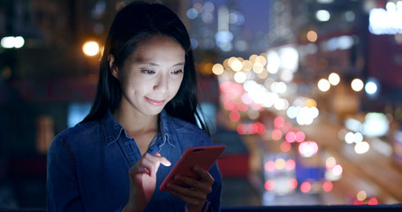 Woman use of smart phone over traffic background at night