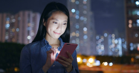 Woman use of mobile phone in city at night
