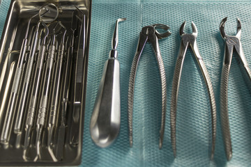 a medical tray with dental instruments, a mirror and a probe. surgical instruments for tooth extraction. medical blue napkin. background