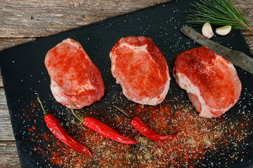 Close up of steak with rosemary and spices on dark rustic background.
