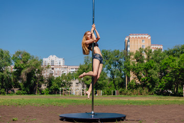 Fit attractive girl dancing near portable pole at summer day © Smile