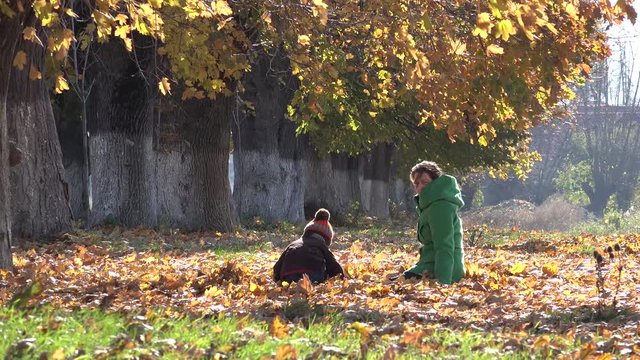 Mother and son fighting with autumn leaves, priceless care