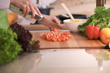 Close Up of human hands cooking vegetable salad in kitchen on the glass table with reflection. Healthy meal, and vegetarian food concept