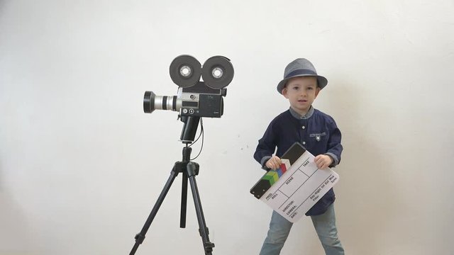 Funny child holding a clapboard, little director having fun, old camera