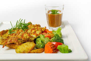 Grilled Chicken Steak top with rosemary with a glass of black pepper gravy, potato and mix vegetable in white plate on white background