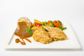 Grilled chicken breast with vegetable, baked potatoes, and a glass of black pepper gravy on white background