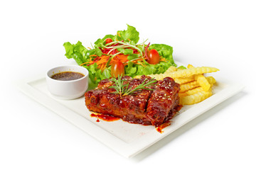 Roasted barbecue pork ribs served with french fries and salad on white background