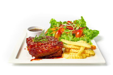 Roasted barbecue pork ribs served with french fries and salad on white background