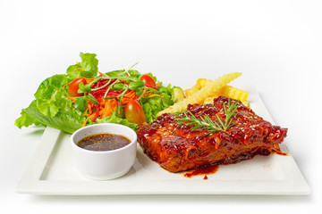 Roasted barbecue pork ribs served with french fries and salad on white background