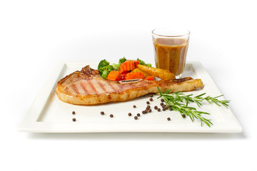 Grilled pork chop steak served with vegetable,fried potatoes and black pepper gravy on white background
