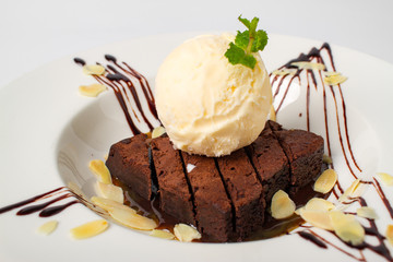 Homade chocolate brownies topped with vanila ice cream in white plate on white background