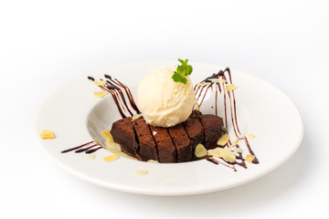 Homade chocolate brownies topped with vanila ice cream in white plate on white background