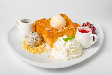 Desserts, Toast topped with vanilla ice cream, served with whipping cream, grape, banana, bean, honey and strawberry sauce on white background
