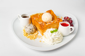 Desserts, Toast topped with vanilla ice cream, served with whipping cream, grape, banana, bean, honey and strawberry sauce on white background