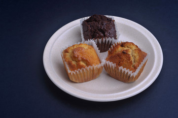 Delicious muffins on a plate with dark background. Muffin is an individual-sized, baked product.