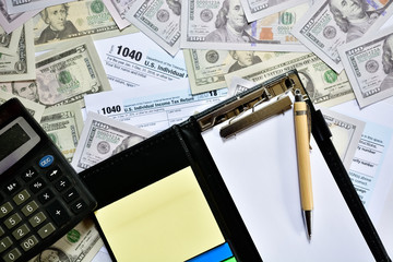 Tax form with notepad, pen and calculator on table. 