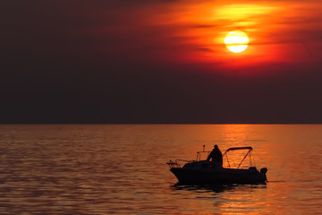 wunderschöner oranger Sonnenuntergang mit Motor Boot Silhouette