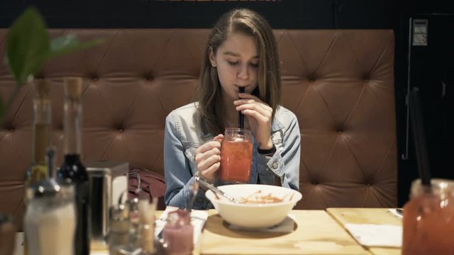 Young girl drinking cocktail sitting in cafe 
