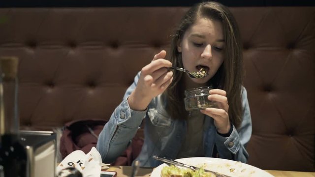 Teenage girl eating meal sitting in cafe 
