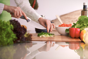 Close Up of human hands cooking vegetable salad in kitchen on the glass table with reflection. Healthy meal, and vegetarian food concept