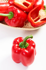 Red peppers with wicker basket on white background, concept of healthy nutrition