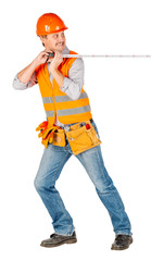 builder in a helmet holding tape-measure in his hands and looking at camera