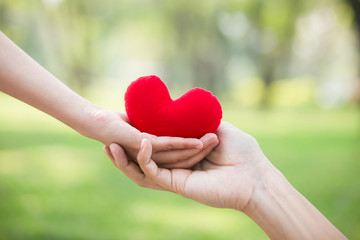 Obraz na płótnie Canvas Hand giving red heart to hand. Love , health care , health insurrance concept.