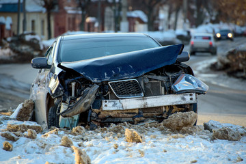 Car crash accident on street, damaged automobile after collision in city. Winter road, snowdrifts.