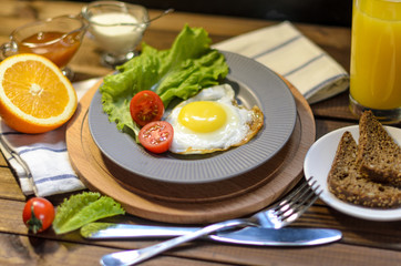 English Breakfast: fried egg, juice, cherry tomatoes, lettuce, grain bread, sauce, top view.