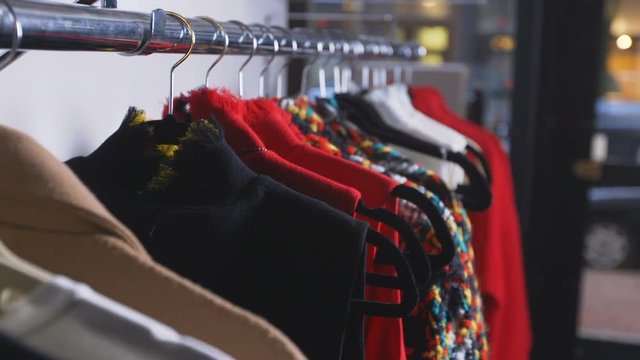 Rack of designer clothes, hand comes to grab one of the jackets