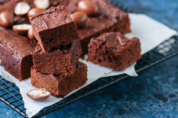 Dark chocolate brownie squares on a wire rack decorated with creamy chocolate eggs. Blue stone background.