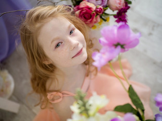 Obraz na płótnie Canvas The beautiful face of a redheaded child is 9 years old in freckles in flowers. Spring