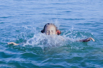 Vacations at sea. Portrait of young beautiful girl having fun in the water of transparent sea. (Holiday, rest, travel, childhood concept)