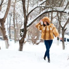 Young beautiful girl in a fur hat and a red fox fur coat