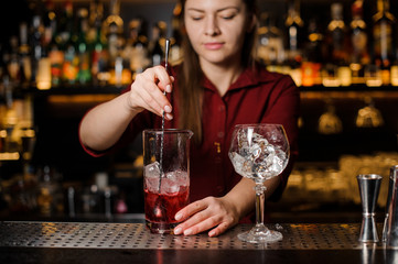 Beautiful female barman stirring sweet alcoholic drink with ice