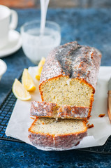 Homemade lemon poppy seed pound cake on a wire rack. Blue stone background. Close up.