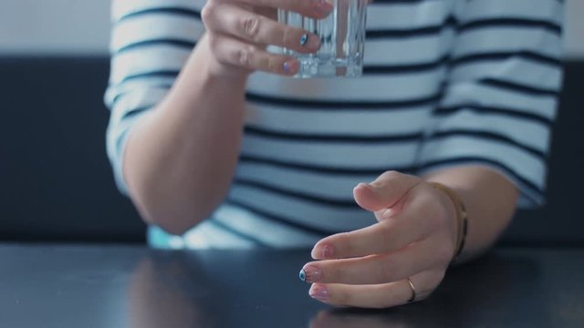 closeup of woman's hand with glass of water touching it and drinking