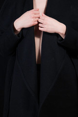 Detail of sexy lady in long coat posing in studio, dark background. Elegant woman. Erotic noir concept.