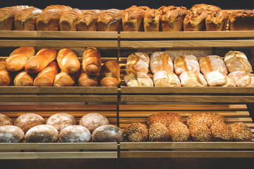 different fresh bread on the shelves in bakery - obrazy, fototapety, plakaty