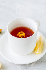 A cup of red herbal tea on a white stone backdrop. Close up.